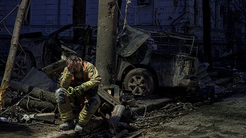 Un soccorritore riposa vicino a un edificio universitario distrutto da un attacco missilistico russo su Sumy, 13 aprile 2025