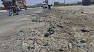 A motorcycle and other vehicles drive past the site of a suicide bombing on a highway on the outskirts of the city of Khuzdar, in southwestern Pakistan, on 21 May, 2025.