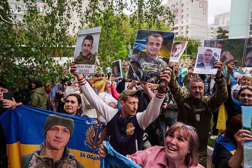 Relatives of missing and imprisoned Ukrainian soldiers show photographs to servicemen returned from captivity in a POW exchange in Ukraine, Tuesday, May 6, 2025. 