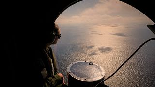 Un membro dell'equipaggio di un aereo della Marina francese osserva il mare durante un'esercitazione militare della NATO e una missione di rilevamento di mine marine sopra il Mar Nero, 9 aprile 2025
