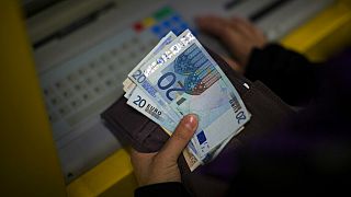 FILE: A woman holds euros bills after withdrawing her money from a cash machine in Barcelona, Spain, Wednesday Jan. 23, 2013.