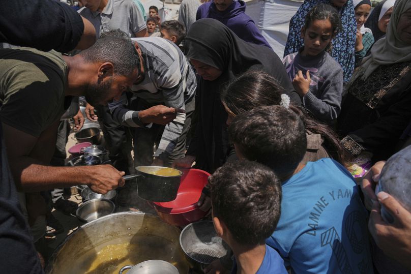 نازحون فلسطينيون يصطفون للحصول على وجبات مقدّمة من مطبخ خيري داخل مخيم خيام في مدينة غزة، يوم الأربعاء 21 أيار/مايو 2025.