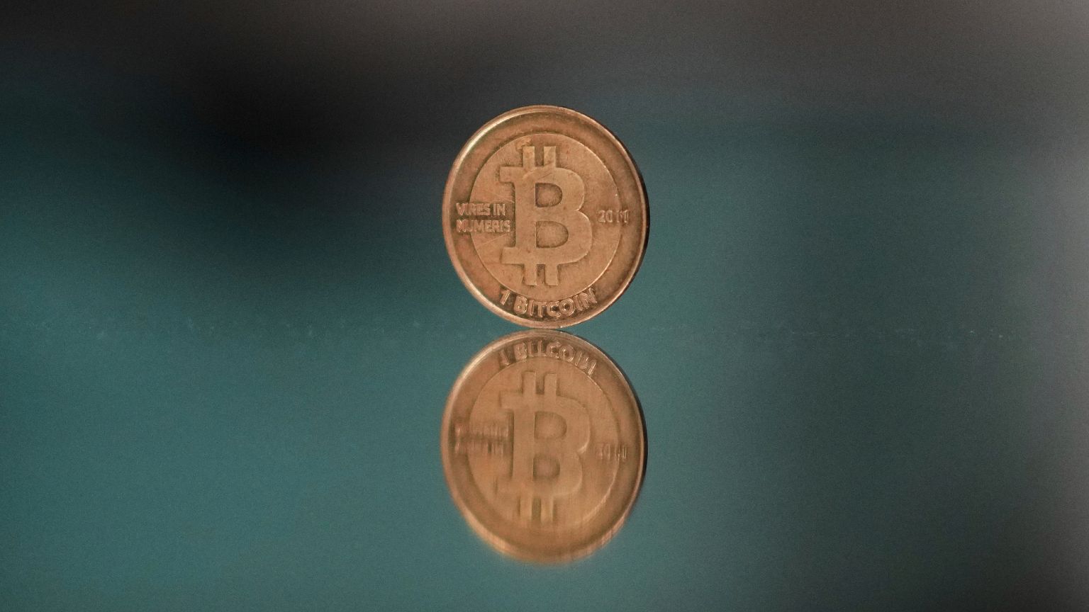 A one bitcoin token reflects as it is placed on a mirror in Prague, Czech Republic, Sunday, May 11, 2025.