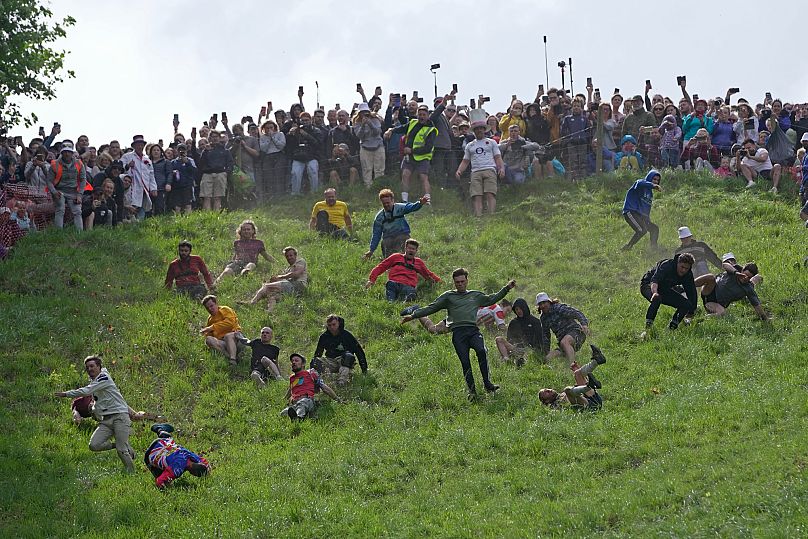 Participants compete in the men's downhill race during the Cheese Rolling contest at Cooper's Hill, 2023.