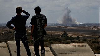 People watch smoke rising to the sky after an explosion in the Gaza Strip as they visit a sightseeing area in Sderot, southern Israel, Thursday, May 22, 2025