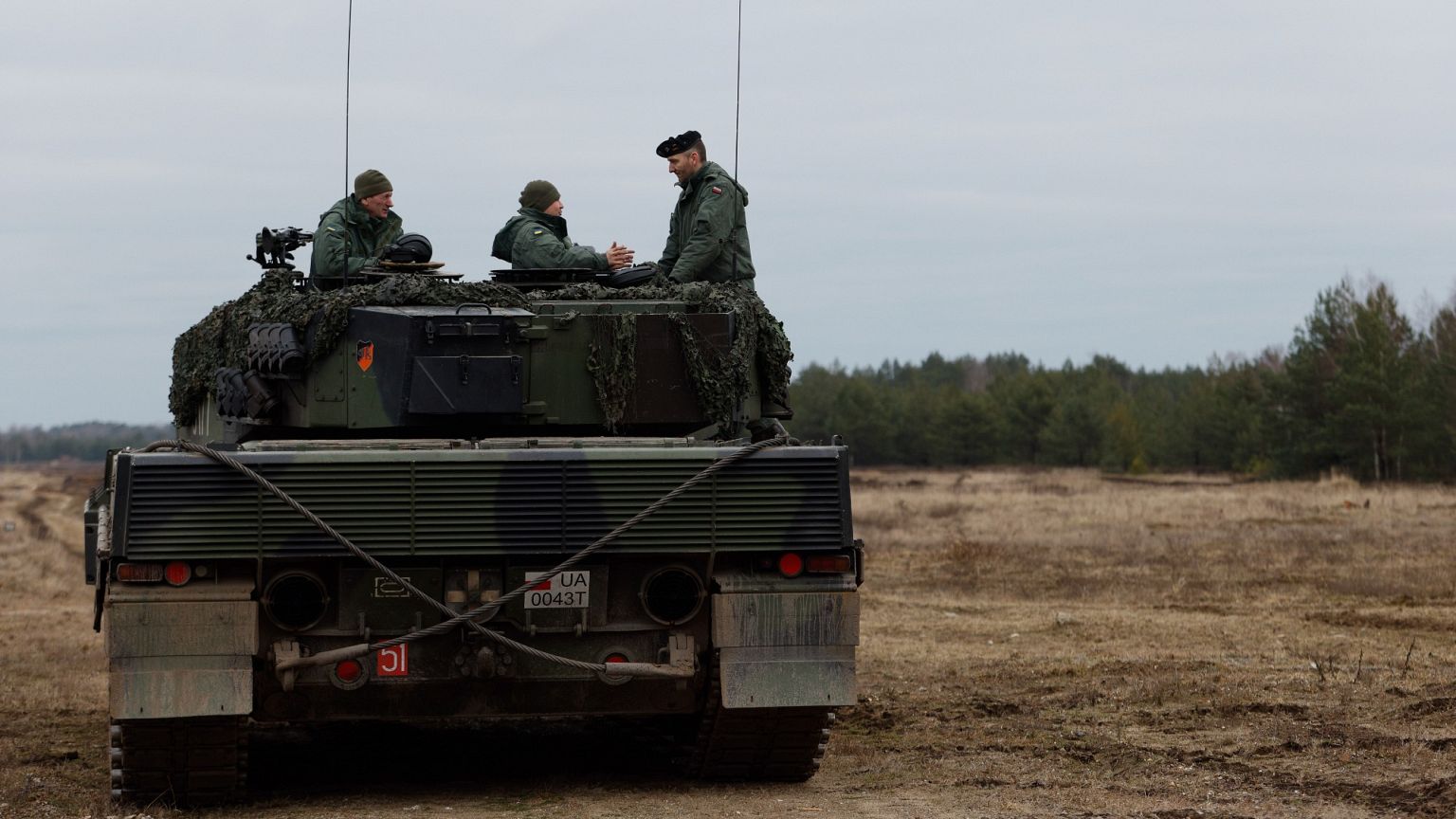 FILE: Ukrainian and Polish soldiers sit on top of a Leopard 2 tank during a training at a military base and test range in Swietoszow, 13 February 2023