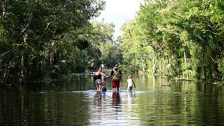 Dustin Holmes, second from right, holds hands with his girlfriend, Hailey Morgan, while returning to their flooded home after Hurricane Helene.