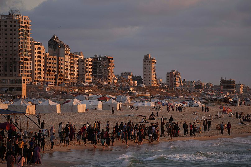 Displaced Palestinians walk along a makeshift tent camp at the shore of Gaza City, 22 May, 2025