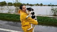 A woman carries a dog along a flooded highway after heavy rains in Campana, Argentina, Saturday, May 17, 2025.