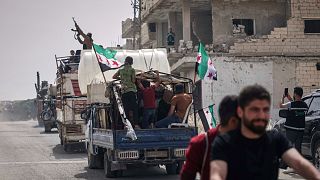 A man fires into the air from one of the trucks carrying some of the 60 displaced families who, supported by an NGO, are returning to their village after more than five years 