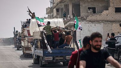 A man fires into the air from one of the trucks carrying some of the 60 displaced families who, supported by an NGO, are returning to their village after more than five years 