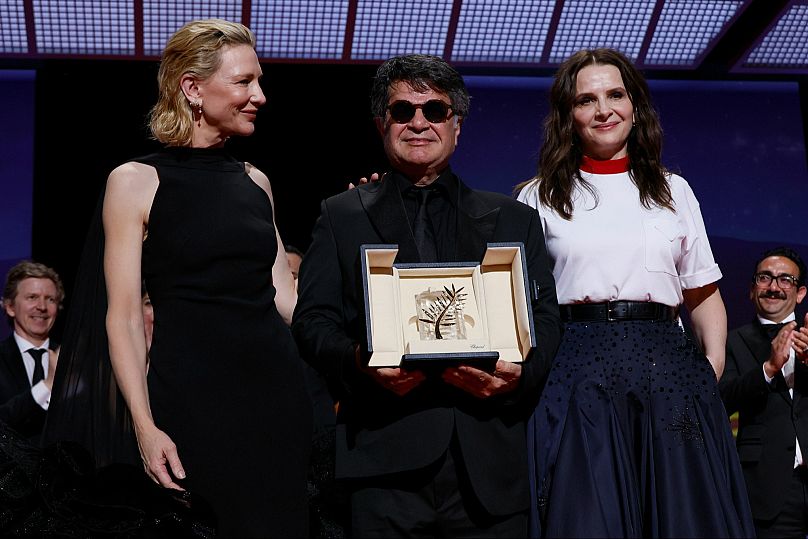 Director Jafar Panahi, centre, accepts the Palme d'Or for the film 'It Was Just an Accident', as he poses with Cate Blanchett, left, and jury president Juliette Binoche.