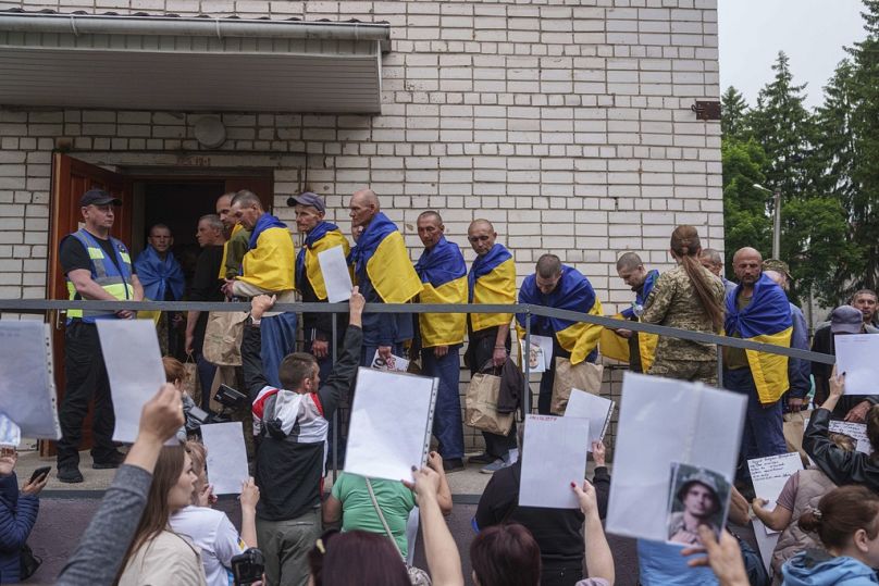 People holding photos of their missed relatives as Ukrainian soldiers return home during POWs exchange between Russia and Ukraine, in Chernyhiv region, Saturday, May 24 2025.