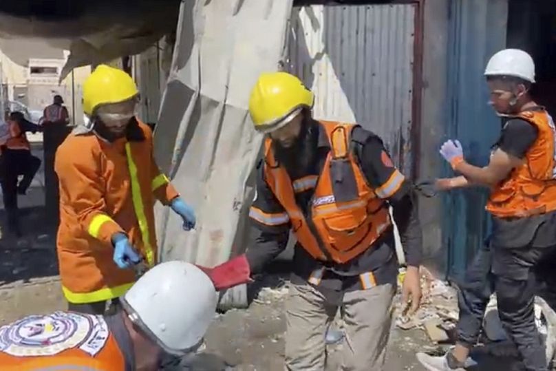 عمال الدفاع المدني في غزة وهم يجمعون رفات بشرية بعد غارة إسرائيلية على منزل في خان يونس أسفرت عن مقتل تسعة من أبناء طبيبة كانت في عملها، السبت 24 أيار/ مايو 2025.