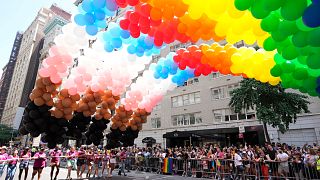 Rainbow balloons are carried down the parade route a NYC Pride March.