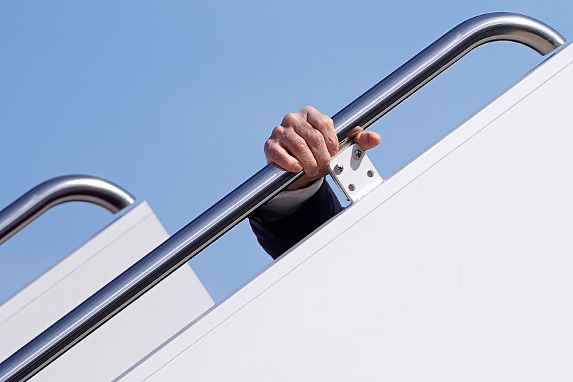 La mano de Joe Biden agarrada a la barandilla de las escalerillas de un avión en el momento del tropiezo.