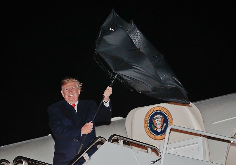 Donald Trump tiene un percance con su paraguas mientras embarca en el Air Force One.
