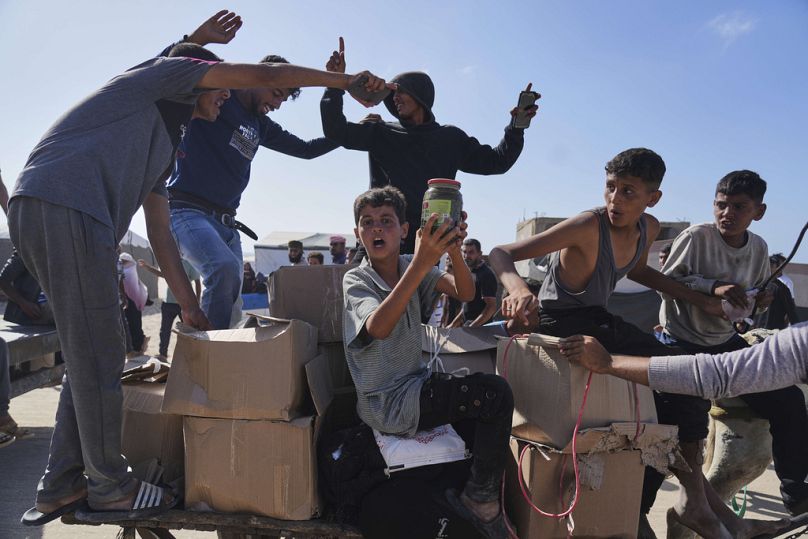 Palestinesi trasportano scatole di aiuti umanitari consegnati dalla Gaza humanitarian foundation a Rafah, nel sud della Striscia di Gaza, 27 maggio 2025