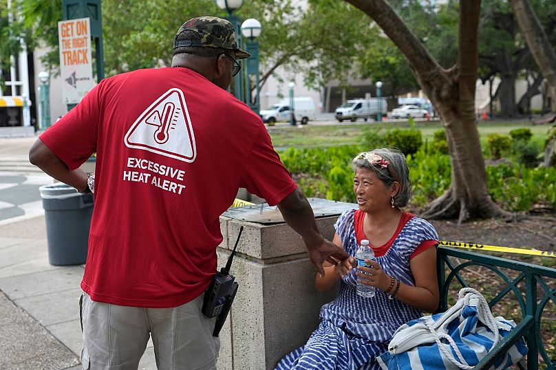 Distributing bottles of water and other supplies to the homeless population, helping them manage high temperatures in Miami.