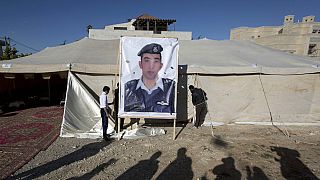 FILE: Workers raise a banner with a photo of Jordanian pilot Lt. Mu’ath al-Kaseasbeh in Amman, Jordan, Jan. 30, 2015