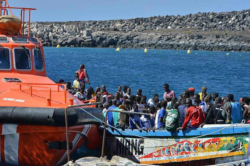 Os migrantes esperam para desembarcar de um pequeno barco em La Restinga, na ilha canária de El Hierro, a 21 de outubro de 2023