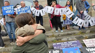 People hug as demonstrators hold a banner representing anonymous sexual assault victims in Vannes, 28 May, 2025 