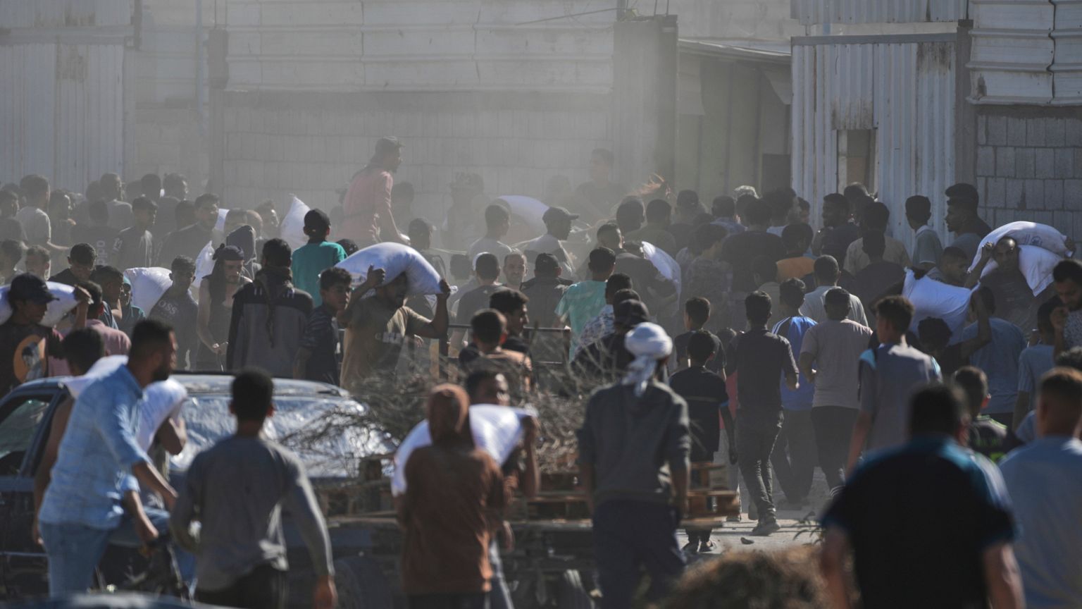 Palestinians carry bags of flour after storming a U.N. World Food Program warehouse in Zawaida, Central Gaza Strip, on Wednesday, May 28, 2025.