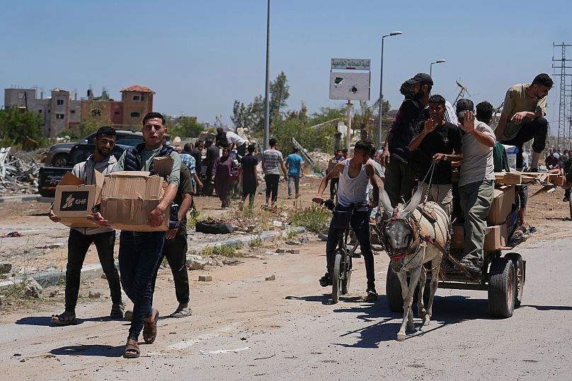 Palestinos transportan paquetes de ayuda humanitaria en Jan Younis, 29 de mayo de 2025.