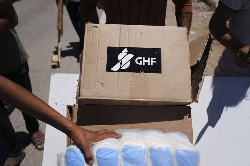 Des Palestiniens transportent des boîtes et des sacs contenant de la nourriture et des paquets d'aide humanitaire livrés par la Fondation humanitaire de Gaza le 29 mai 2025