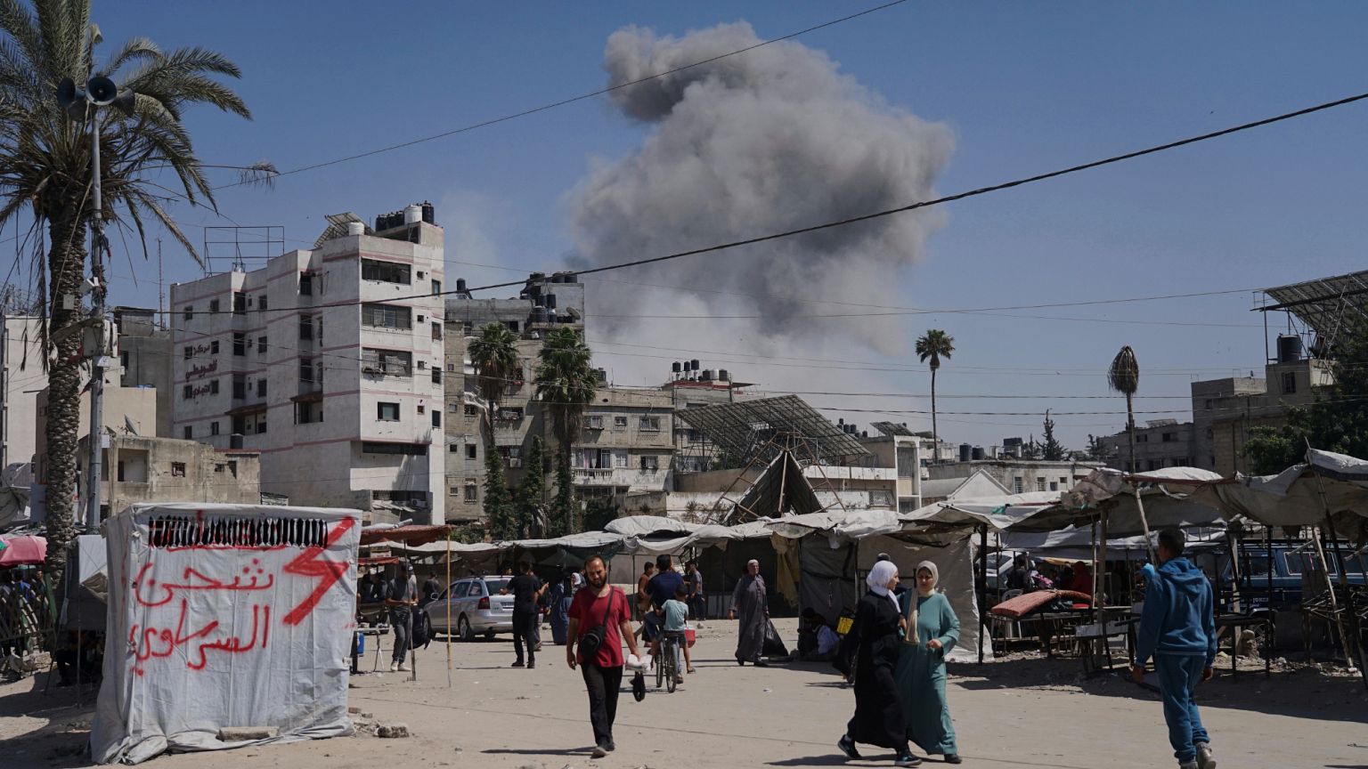 El humo se eleva en el cielo tras un ataque aéreo israelí mientras los palestinos caminan por la ciudad de Gaza, 30 de mayo de 2025. El humo se eleva en el cielo tras un ataque aéreo israelí mientras los palestinos caminan por la ciudad de Gaza, 30 de mayo de 2025.