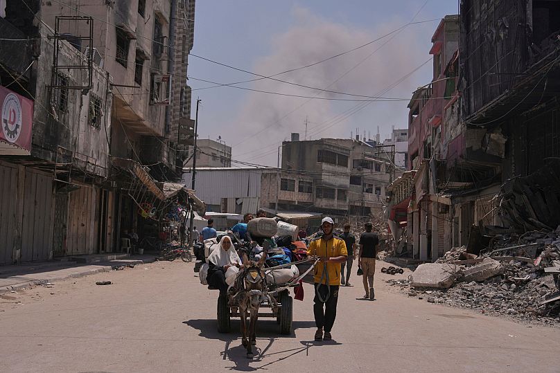 El humo se eleva al cielo tras un ataque aéreo israelí mientras los palestinos que huyen de Jabalia se mueven con sus pertenencias en la ciudad de Gaza, el 30 de mayo de 2025.