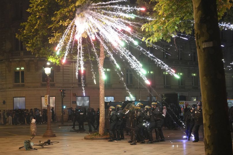 Fireworks explode over riot police officers on the Champs-Elysees avenue after the Champions League final on Sunday, 1 June 2025