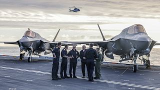 Britain's Prime Minister Keir Starmer, center left, and Defence Secretary John Healy, center right, talk with naval officers on the flight deck of HMS Prince of Walesin Plymou