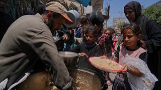 Palestinian children get food at a food distribution kitchen in Deir al-Balah, Gaza Strip, Friday, May 30, 2025. 