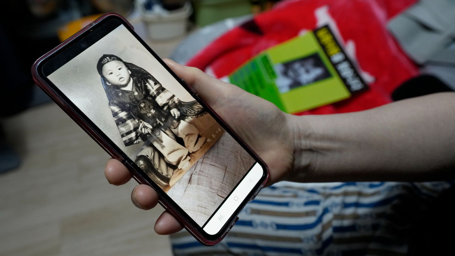 FILE - A South Korean woman holds a smartphone displaying a photo of her son, who went missing in 1975, as she sits in her motel room in Seoul, 5 March 2024