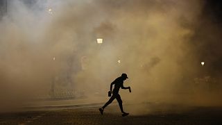 A man walks past teargas during incidents after the Champions League final soccer match between Paris Saint-Germain and Inter Milan in Paris, 1 June, 2025