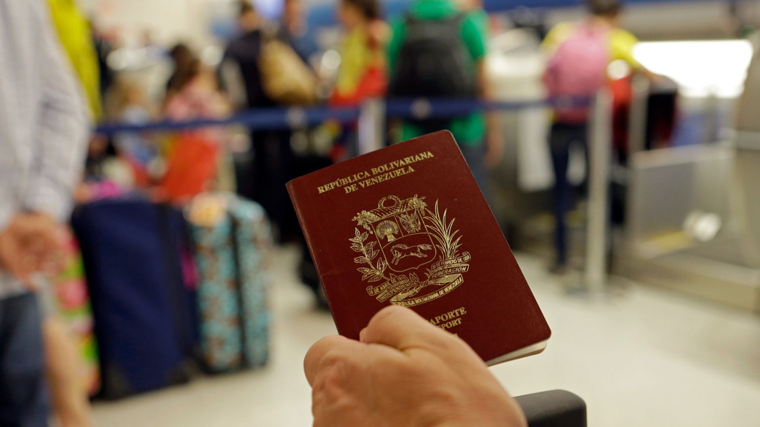 FILE: A passenger holds his Venezuelan passport as he prepares to travel to Venezuela at Miami International Airport in Miami, 25 June 2014