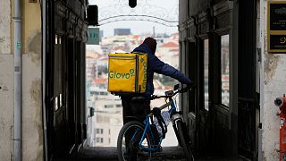 A Glovo delivery rider stops at an alley in Lisbon. The company has been fined by the European Commission for €106 million.