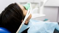 A woman inhales nitrous oxide in a medical office.