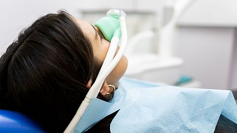 A woman inhales nitrous oxide in a medical office.