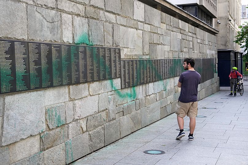 Un homme regarde le Mémorial de la Shoah de Paris barbouillé de peinture verte, le samedi 31 mai 2025
