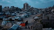 Palestinians displaced by the Israeli air and ground offensive on the Gaza Strip, walk on an area at a makeshift tent camp during the dusk in Gaza City, 2 June 2025