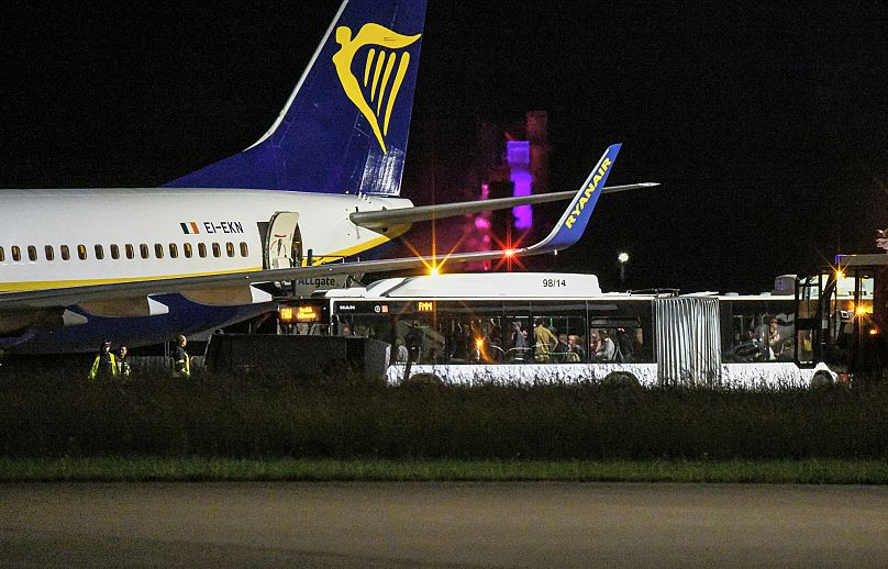 Un autobús lleno de viajeros se encuentra delante de un avión de pasajeros de Ryanair en la plataforma del aeropuerto de Memmingen, en el sur de Alemania.