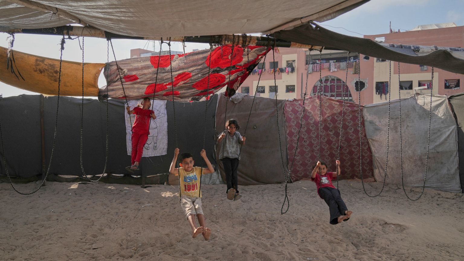 Displaced Palestinian children play on swings at a makeshift tent camp in Khan Younis, Gaza, on Wednesday, June 4, 2025.