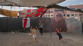 Displaced Palestinian children play on swings at a makeshift tent camp in Khan Younis, Gaza, on Wednesday, June 4, 2025.
