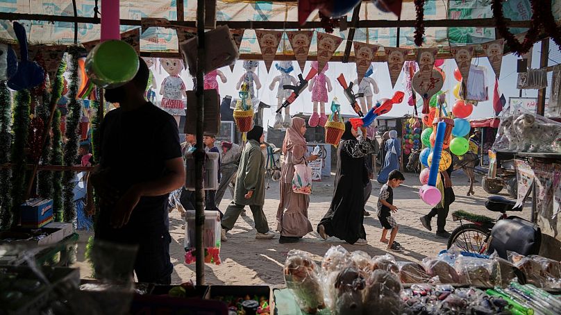 Palestinianos passam por uma loja de brinquedos num mercado antes do feriado muçulmano de Eid Al Adha.