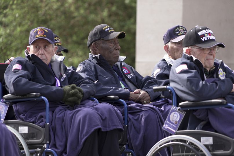En el centro, el veterano Calvin Shiner, un hombre de 102 años que fue reclutado en 1943 por el Ejército de EE.UU., entonces racialmente segregado.