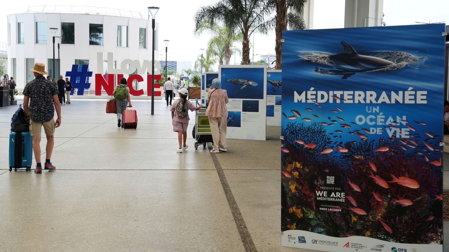 People leave the airport near signs ahead of the upcoming UN Ocean Conference in Nice.