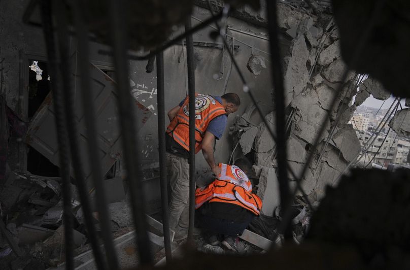 عمال الدفاع المدني الفلسطينيون يبحثون بين الأنقاض بعد غارة جوية إسرائيلية على مبنى سكني في مدينة غزة، الخميس 24 أبريل 2025.  