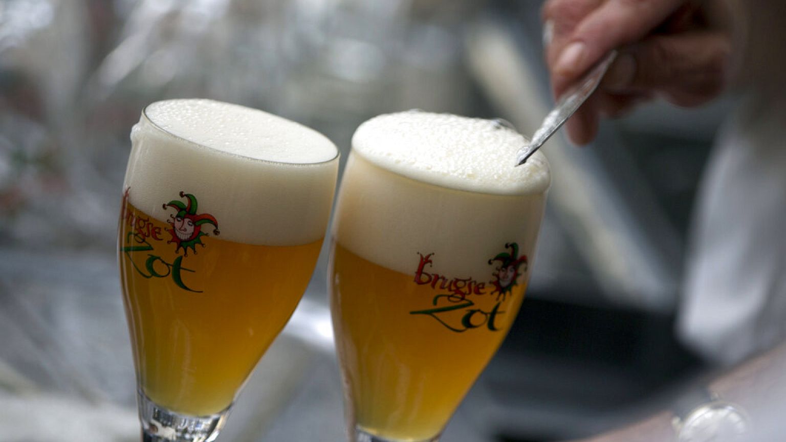FILE - In this file photo dated Thursday, May 26, 2016, a workers scrapes the foam off of a glass of beer before serving, in Bruges, Belgium.